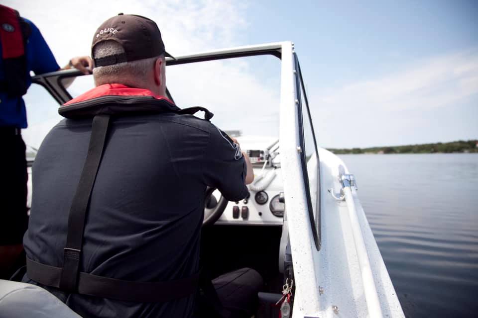 Rural Unit Police Officer driving boat on lake water